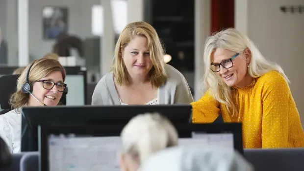 Tre kvinnor kollar på samma datorskärm och diskuterar finansiering för nytt projekt